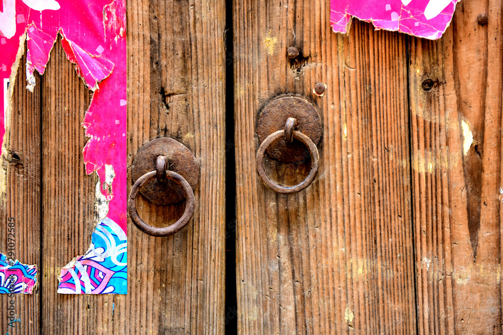 Wall mural ancient wooden gate with two door knocker rings and locks close-up