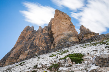 Fototapeta premium Mountain landscape with three imposing peaks agains a blue sky with trailing clouds