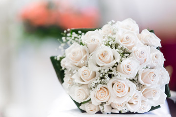 Close up of a wedding bouquet made of pale pink roses, against a bokeh background