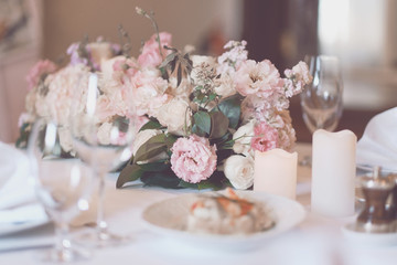 Bouquet on the table. Wine glasses in the foreground. Wedding Banquet or gala dinner. The chairs and table for guests, served with cutlery and crockery.