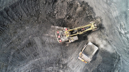 Cable excavator loads overburden from the body of a mining truck.