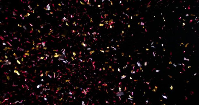Confetti fired in the air during a party. Only confetti on black background of the night. Falling metallic glitter foil confetti multicolor in black background.