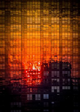 High rise building reflecting on a skyscraper glass facade in Manhattan at sunset