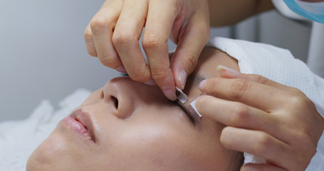 Beauty professional procedures eyelash extension on woman eyes