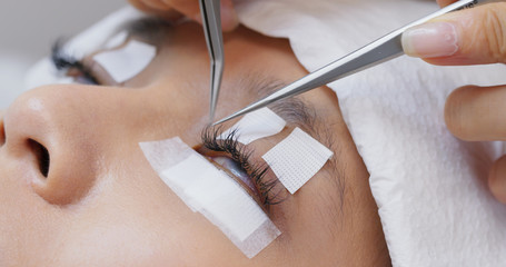 Beauty professional procedures eyelash extension on woman eyes