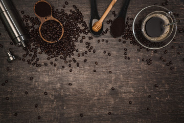 Fototapeta na wymiar Brown coffee beans And a cup of hot coffee placed on a wooden table with honey. Wooden background with espresso and beans. Top view with copy space for your text.