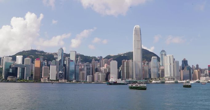 Boats float in front of Hong Kong city skyline in 4k slow motion