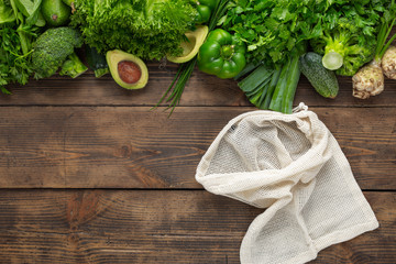 Purchase healthy food. Shopping bag with green vegetable on wooden background top view. Healthy food clean eating