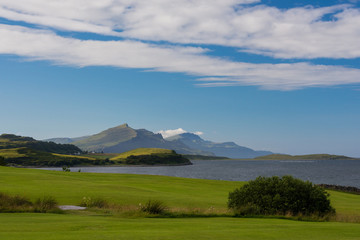 Fototapeta premium Peaceful and iconic landscape of the scottish Skye island, with a green meadow in foreground and distant mountains in the background