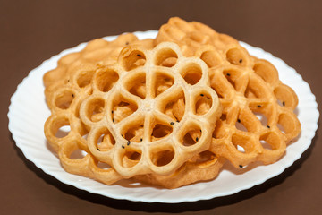 Side view of Kerala dessert Achappam in a plate on brown background 