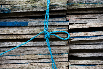 Close up of a stack of wooden boarden held together by a blue nylon rope with a knot in the middle © Roberto