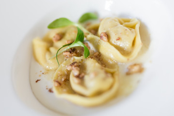 Close up of a dish cotaining three Tortellini with a chestnut and salad topping