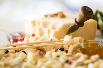 Close up of a tray holding a wheel of cheese, smaller pieces, a cheese knife, chopsticks and a pot...