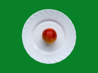 Peach in a white plate, which stands on a green background. Top view