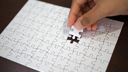 hand pick a piece of jigsaw to connect success on wooden table top selected focus