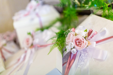 Wedding decorations, with a bouquet of pink roses in foreground, and gift boxes out of focus in the background