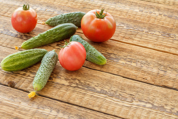 Cucumbers with tomatoes on old wooden boards.