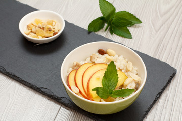 Sorghum salad with nuts and fresh peach on black stone board.