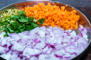 Closeup of Top view of a plate of chopped vegetables of onion, carrot, coriander leaves