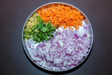 Top view of a plate of slices vegetables of onion, carrot, green chili