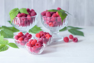 ripe raspberries on a white background. raspberries in glass cups on the table. harvest berries.