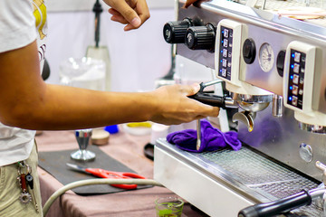 Closeup hands of coffee barista making a fresh coffee by coffee machine for customer in a coffee shop.