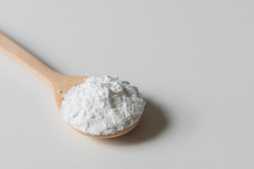 Close-up of tapioca starch or flour powder in wooden spoon on white background