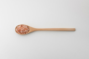 Himalayan salt in wooden spoon on white background
