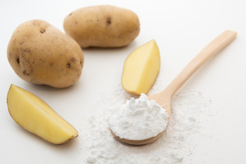 Close-up of potato starch or flour powder in wooden spoon on white background