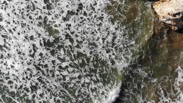 PB155_D-Cinelike, a continuation of shot PB154, Looking directly down at rushing waves with foamy water, Ending with going over cliffs with bushes on top.