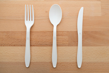 Biodegradable plastic spoon, fork and knife made from starch on wooden background