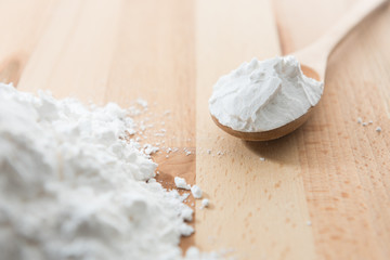 Close-up of tapioca starch or flour powder in wooden spoon with wooden background