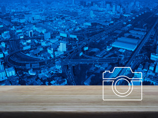 Camera flat icon on wooden table over modern city tower, street, expressway and skyscraper, Business camera service shop concept