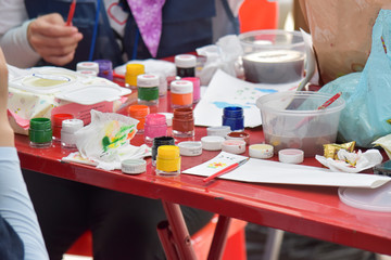 Paint brush, watercolor in the bottle on a red table. Drawing activities for children