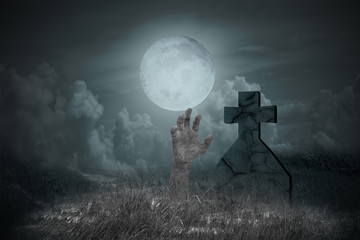 Halloween concept: Zombie hand coming out of grave in full moon night. Spooky Night background.