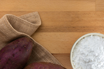 Top view of sweet potato starch in white bowl with sweet potato wooden table background