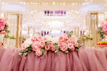 Table decoration with fresh flowers in pastel colors. Elegant dining table in peach-pink color. Luxurious flowers composition. Indoors wedding. Tablecloth lilac color. Beautiful table setting.