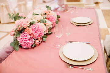 Table decoration with fresh flowers in pastel colors. Elegant dining table in peach-pink color. Luxurious flowers composition. Indoors wedding. Tablecloth lilac color. Beautiful table setting.