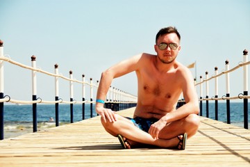 Man sitting on the wooden pier with sea view 