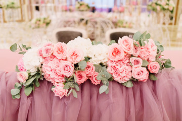 Table decoration with fresh flowers in pastel colors. Elegant dining table in peach-pink color. Luxurious flowers composition. Indoors wedding. Tablecloth lilac color. Beautiful table setting.
