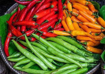 Fresh chili peppers in a basket with vegetables background at a local market in Thailand