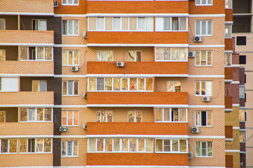 yellow and orange brick building facade with windows and balconies