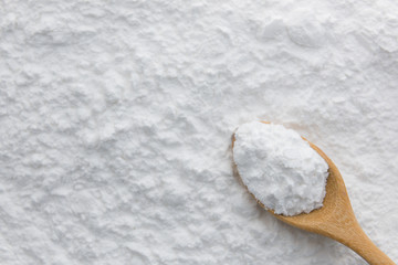Close-up of tapioca starch or flour powder in wooden spoon on white background