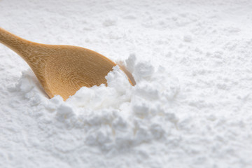 Close-up of tapioca starch or flour powder in wooden spoon on white background