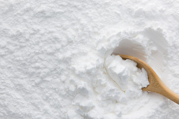 Close-up of tapioca starch or flour powder in wooden spoon on white background