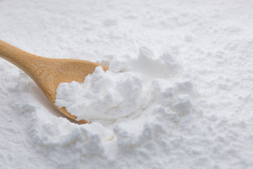 Close-up of tapioca starch or flour powder in wooden spoon on white background