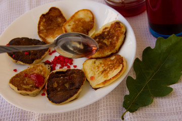 fritters on a white plate watered with berry jam. dessert on a white tablecloth