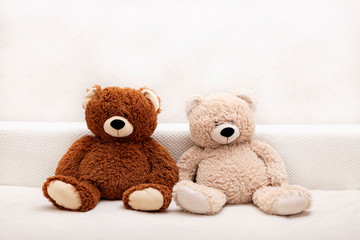 Children's toys - bears of brown and beige color are sitting on the sofa.