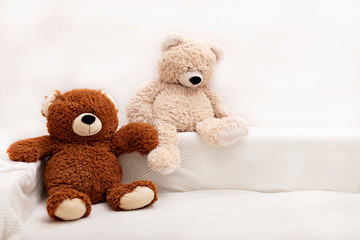 Children's toys - bears of brown and beige color are sitting on the sofa.