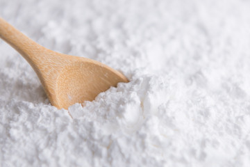Close-up of tapioca starch or flour powder in wooden spoon with white background isolated
